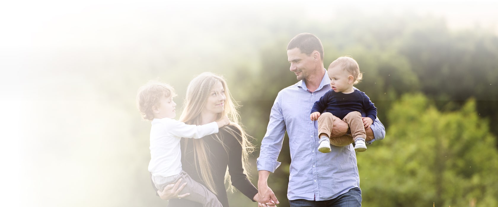 Family walking in park holding hands and kids in lap