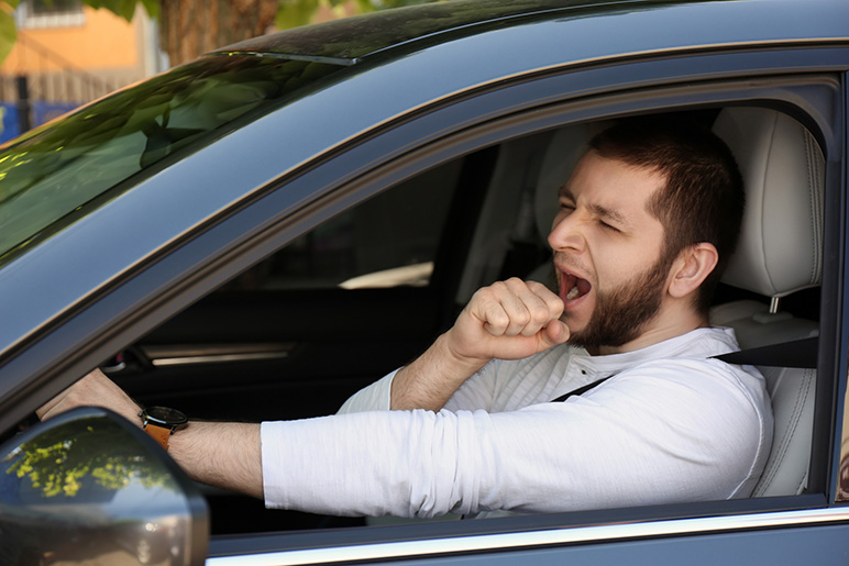 A man yawns while driving