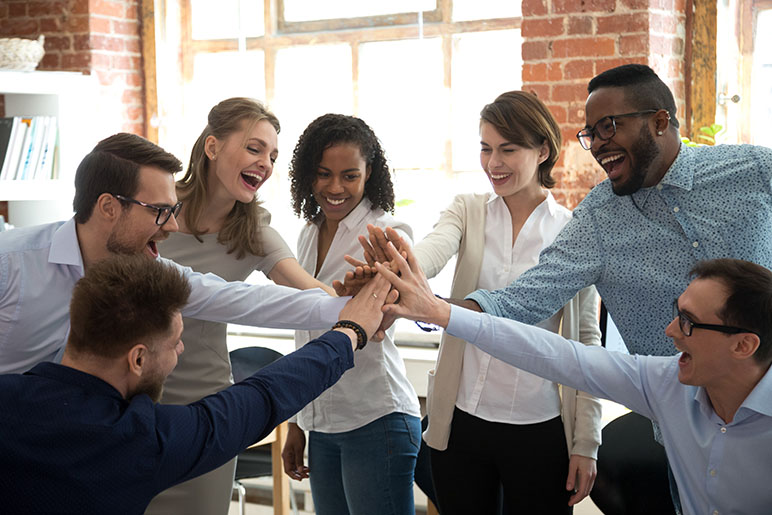 7 employees high-fiving in a circle looking happy and celebrating 