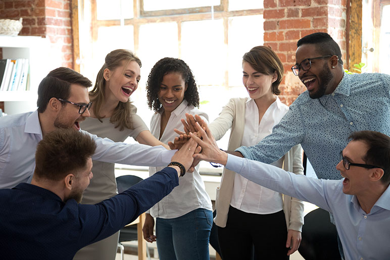 7 employees high-fiving in a circle looking happy and celebrating