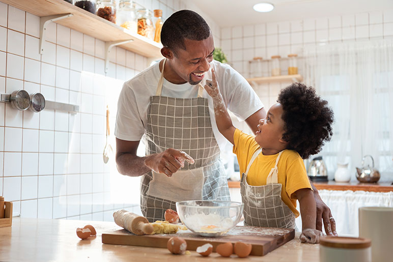 A father and son baking in the kitchen with flour and eggs