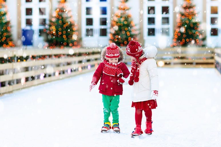 A photo of two young girls ice skating in a park in the winter time