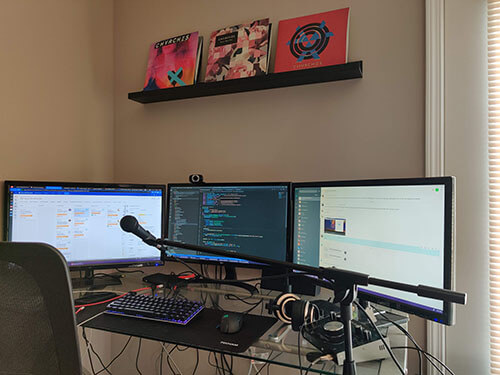 Work from home desk with three large computer monitors,  good quality headphones and a microphone