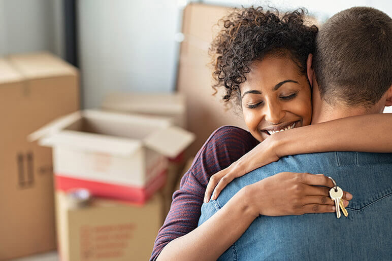 Woman and man hugging with new home keys in their hands