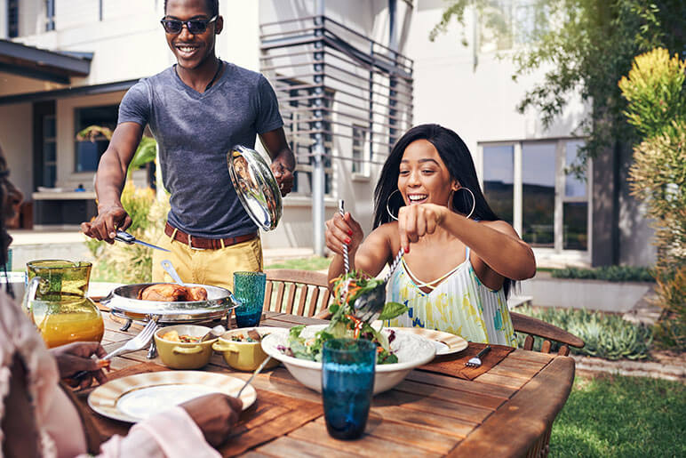 Man and woman with family eating dinner outside during the summer