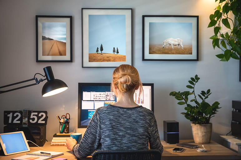 A woman working from home sitting at her computer screen at her desk