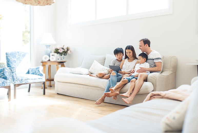 Family of four sitting on the couch looking at an ipad