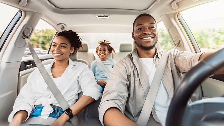Family of three in the car smiling while driving
