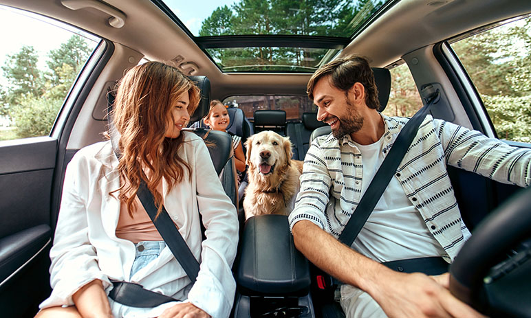 Family of three in the car with their dog sitting in the middle of them