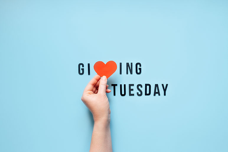 Giving Tuesday graphic with a hand holding a heart at the V in Giving