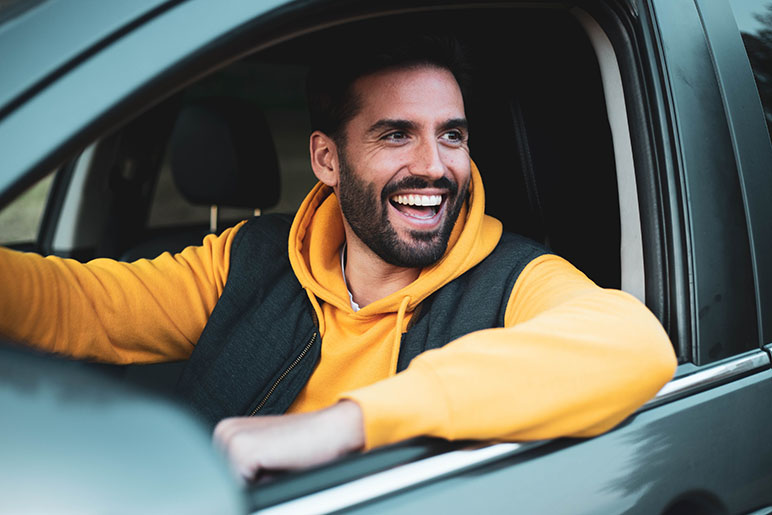 Happy man smiling from inside the driver's seat in his vehicle