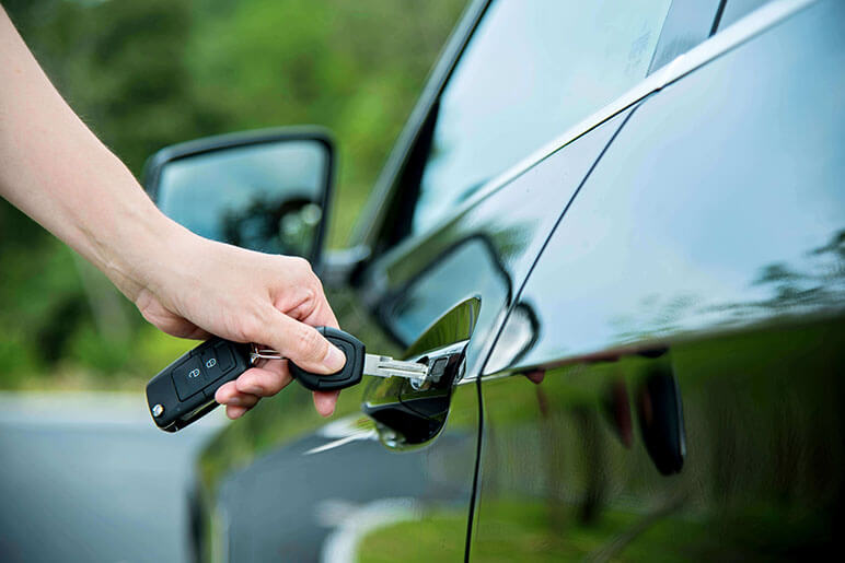 Woman manually locking door to the driver's side of the car