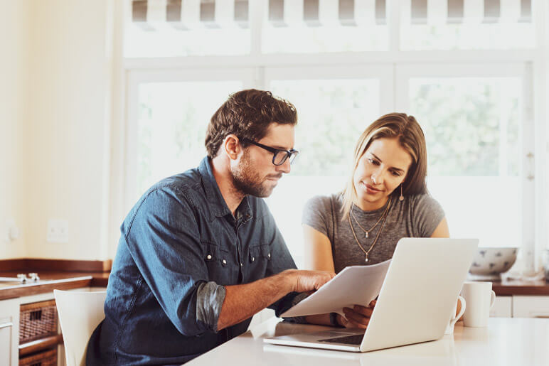 Husband and wife using laptop - checking the premium change on insurance policy