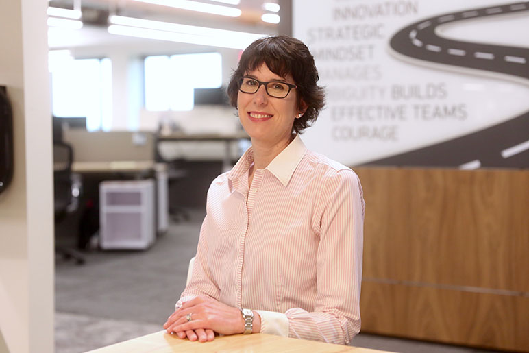 Kristin Keltner sitting at a table with her hands crossed in front of her smiling