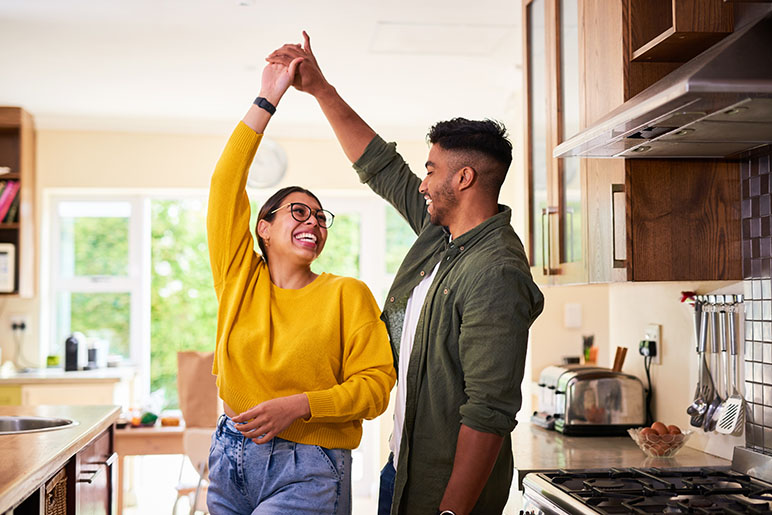 Life insurance options for young adults who are dancing in the kitchen of their home