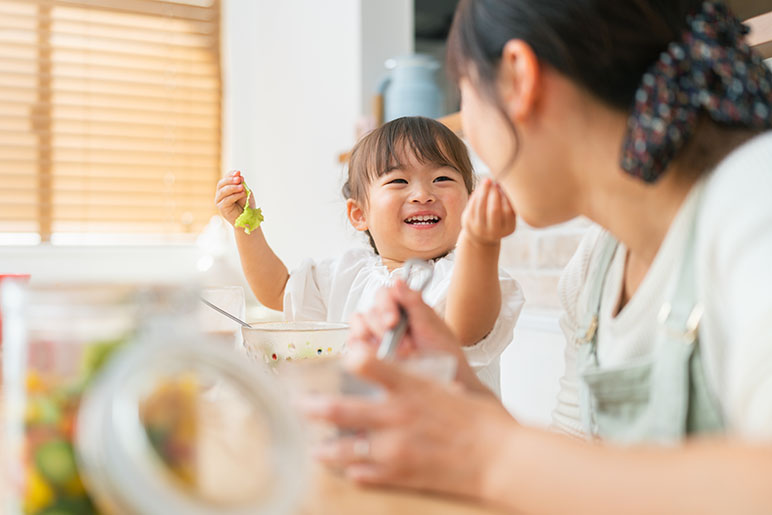 Mom and baby daughter eating salad in the kitchen