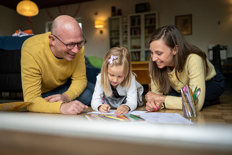 Mom and dad on the ground drawing with their daughter