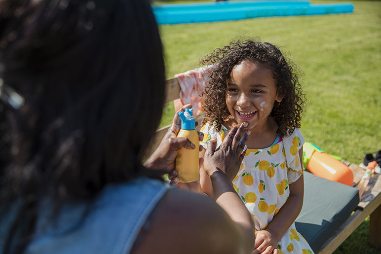 Mom putting sunscreen on her little girl