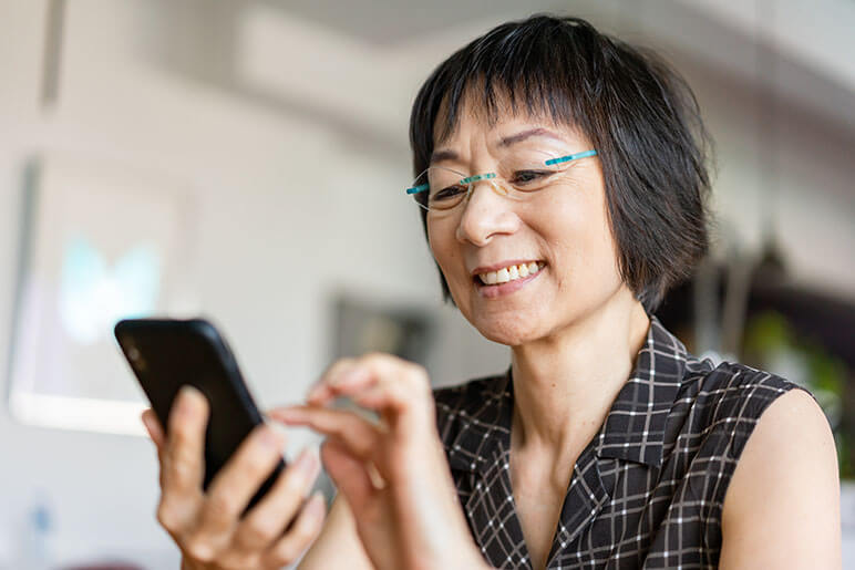 Older woman holding her phone while smiling 