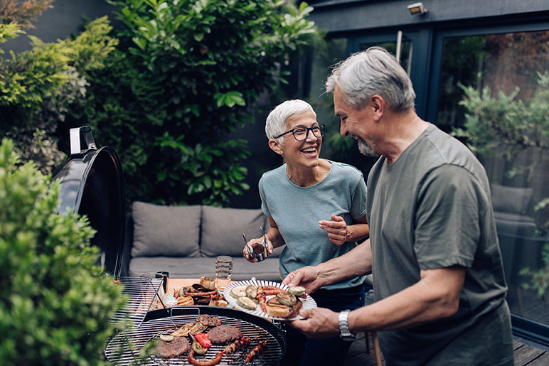 Older couple safely grilling outside