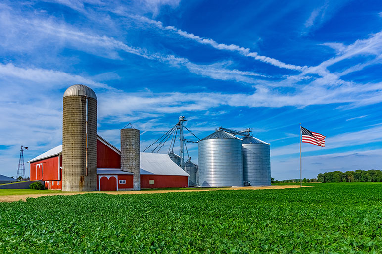 photo of a farm in Indiana with two grain bins and an American flag