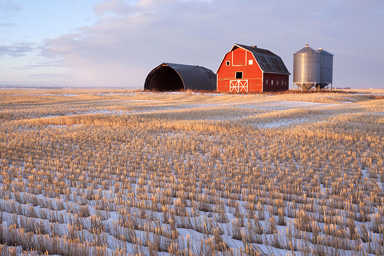 Photo of a farm in the wintertime with a red barn and grain bin