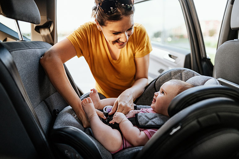 Photo of a mother strapping her baby in a car seat