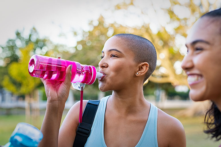 Photo of a young adult drinking a water bottle outside