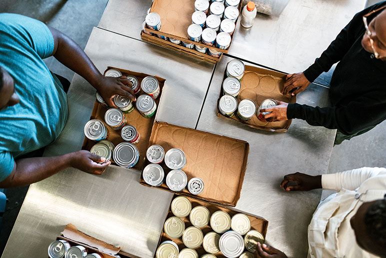 Photo of people volunteering and packaging canned goods