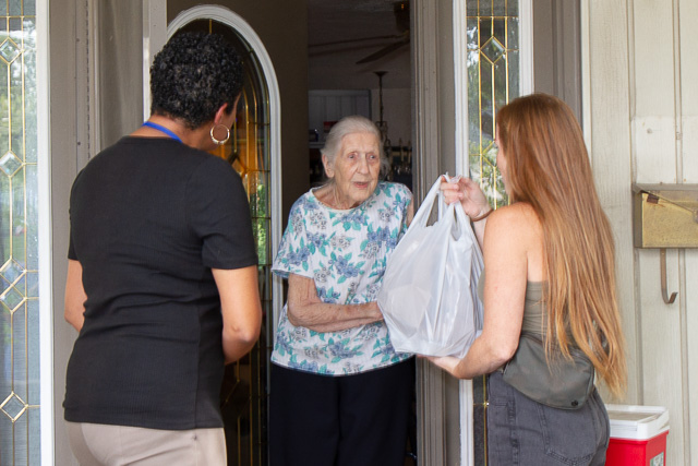 Photo of two women volunteering for Meals on Wheels of Central Indiana and giving a woman groceries