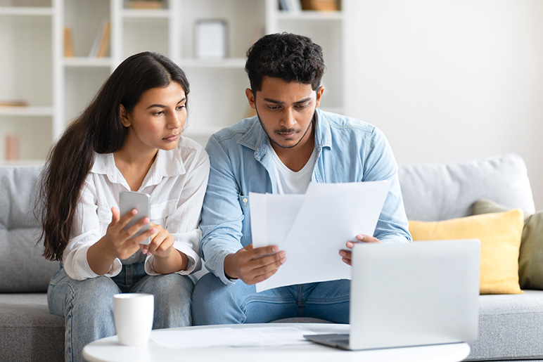 Couple sits on the couch and discusses their budget.
