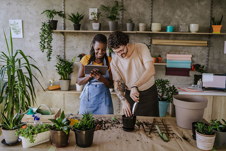 A couple planting plants in pots in a small shop