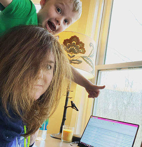 Mom and son at mom's work from home desk looking busy