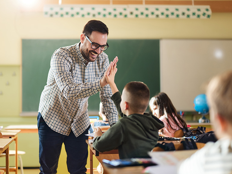 Teacher in the classroom gives a student a high five