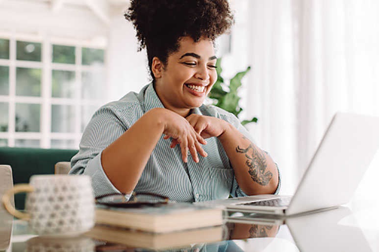 Woman smiling at her computer in her living space