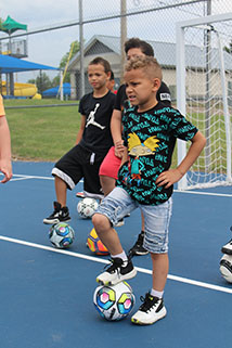 Young boy standing with one leg on top of a soccer ball