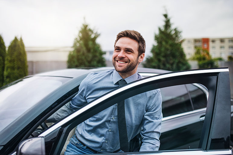 Young man getting out of his car smiling