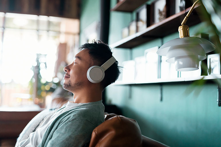 Young man listening to music with his headphones on the couch