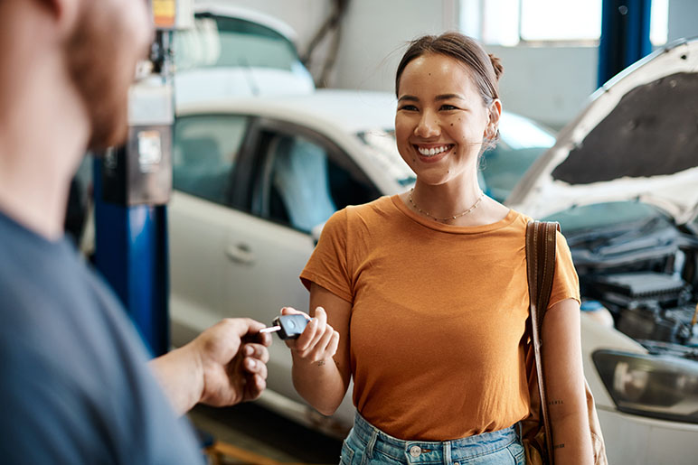 Young woman at a car repair shop getting her keys from the maintenance man